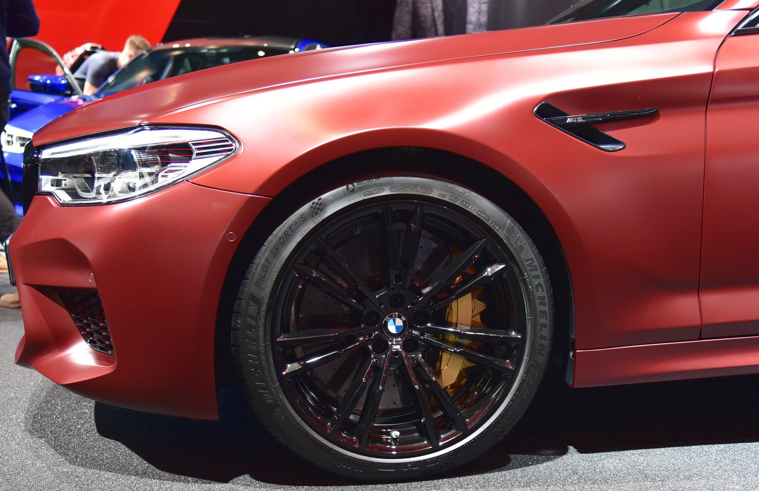 Close-up of black alloy wheel and LED headlight on matte red body