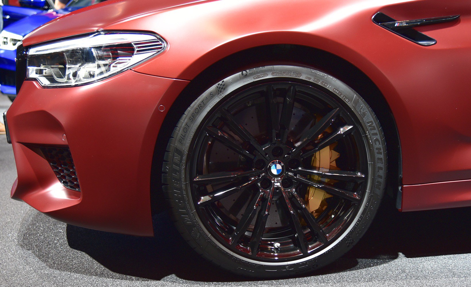 Close-up of BMW front wheel, black alloy rim, headlight, and brake caliper