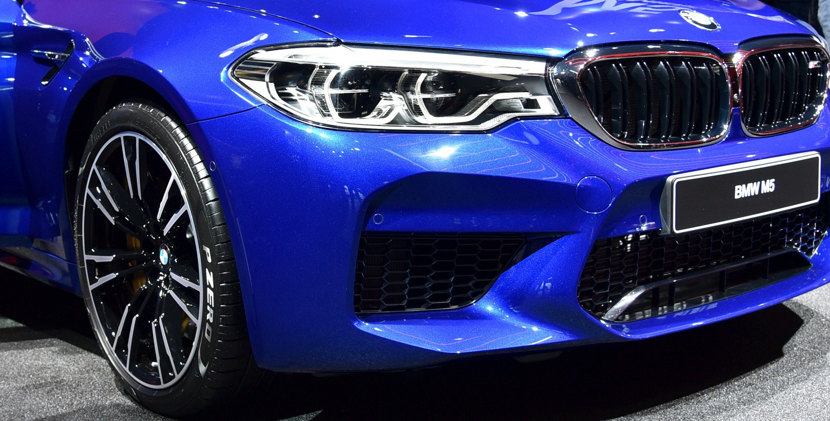 Close-up of front fascia, headlight, grille, and wheel of a sporty blue car