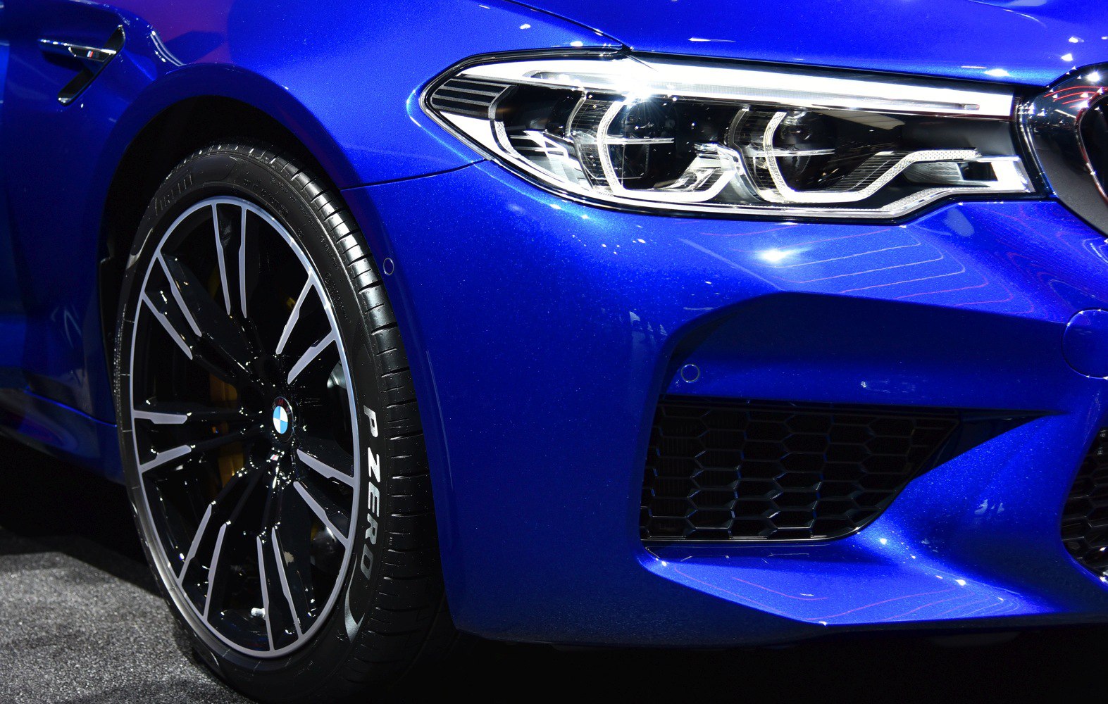 Blue sports sedan front headlight and wheel close-up