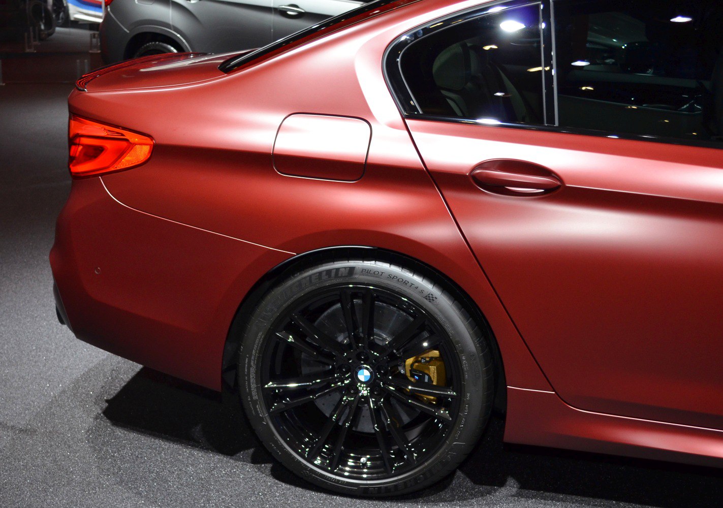 Close-up of rear side with black alloy wheel and red matte paint