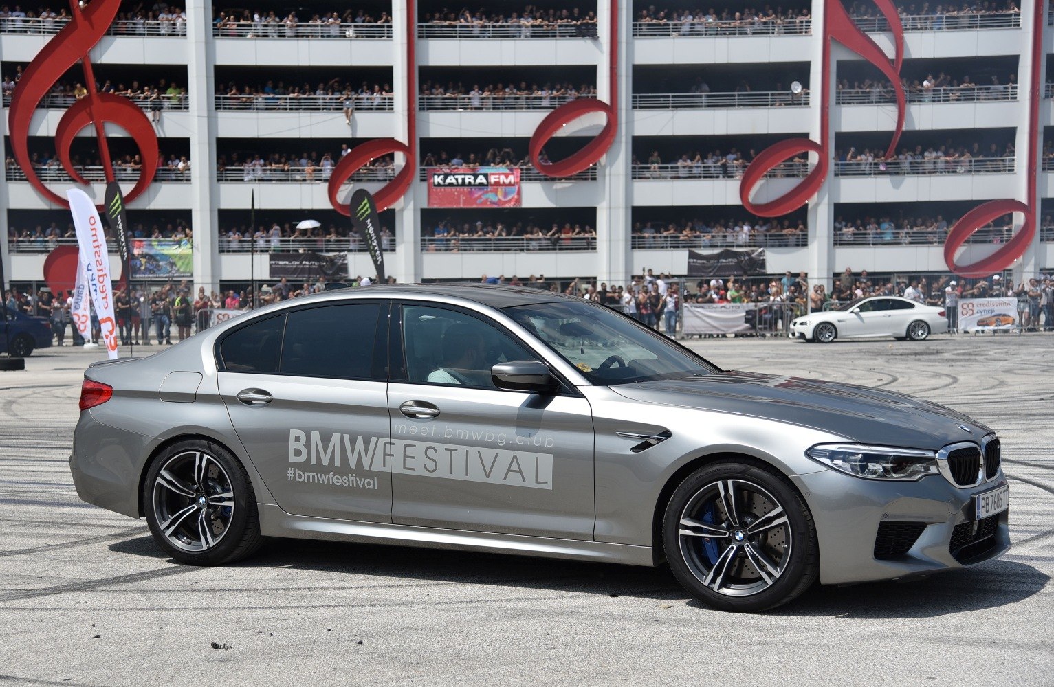 Silver BMW M5 F90 sedan with BMW Festival decals and alloy wheels