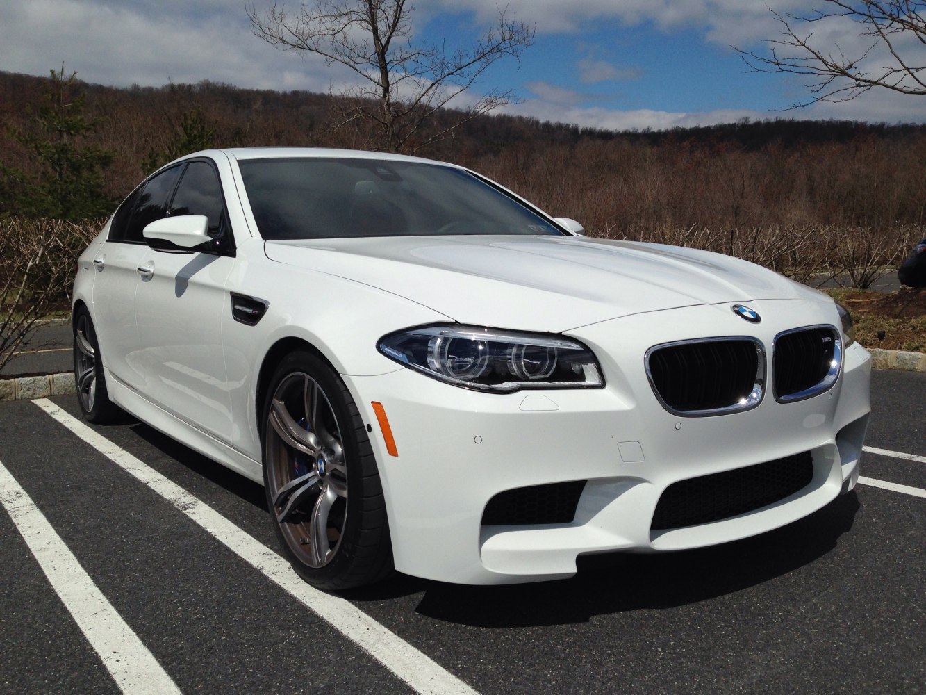 Front side view of a white high-performance luxury sedan with aggressive styling.