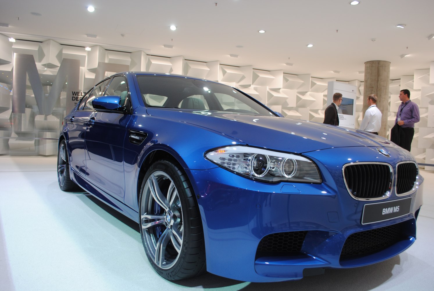 Close-up on front grille, headlights, and alloy wheels of blue sports sedan
