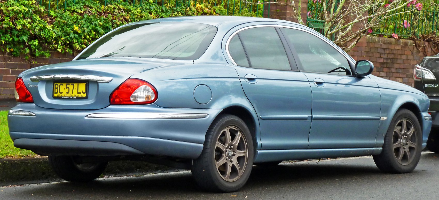 Rear and side view of a light blue sedan with alloy wheels