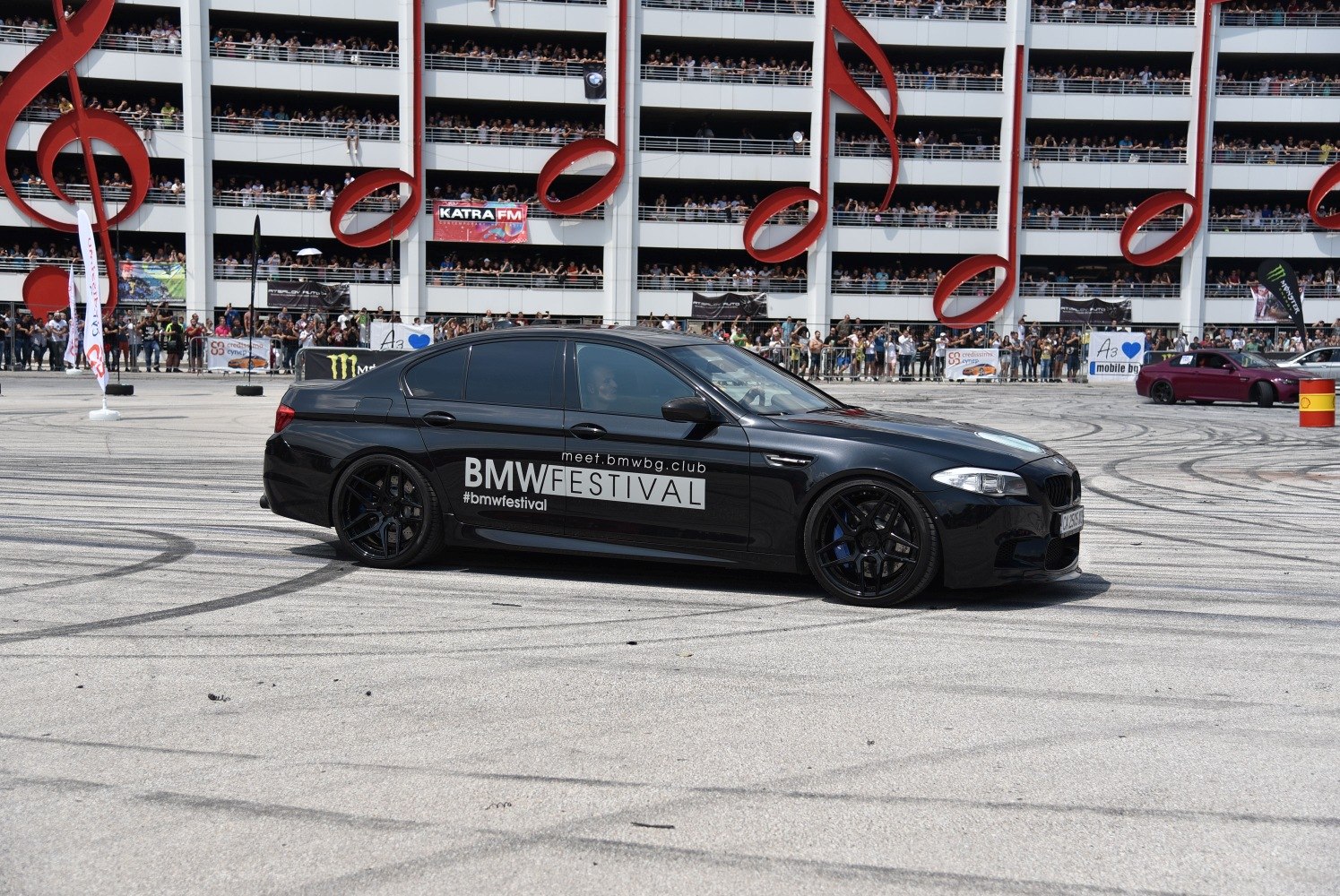 Black sedan with sporty wheels and tinted windows at a BMW event