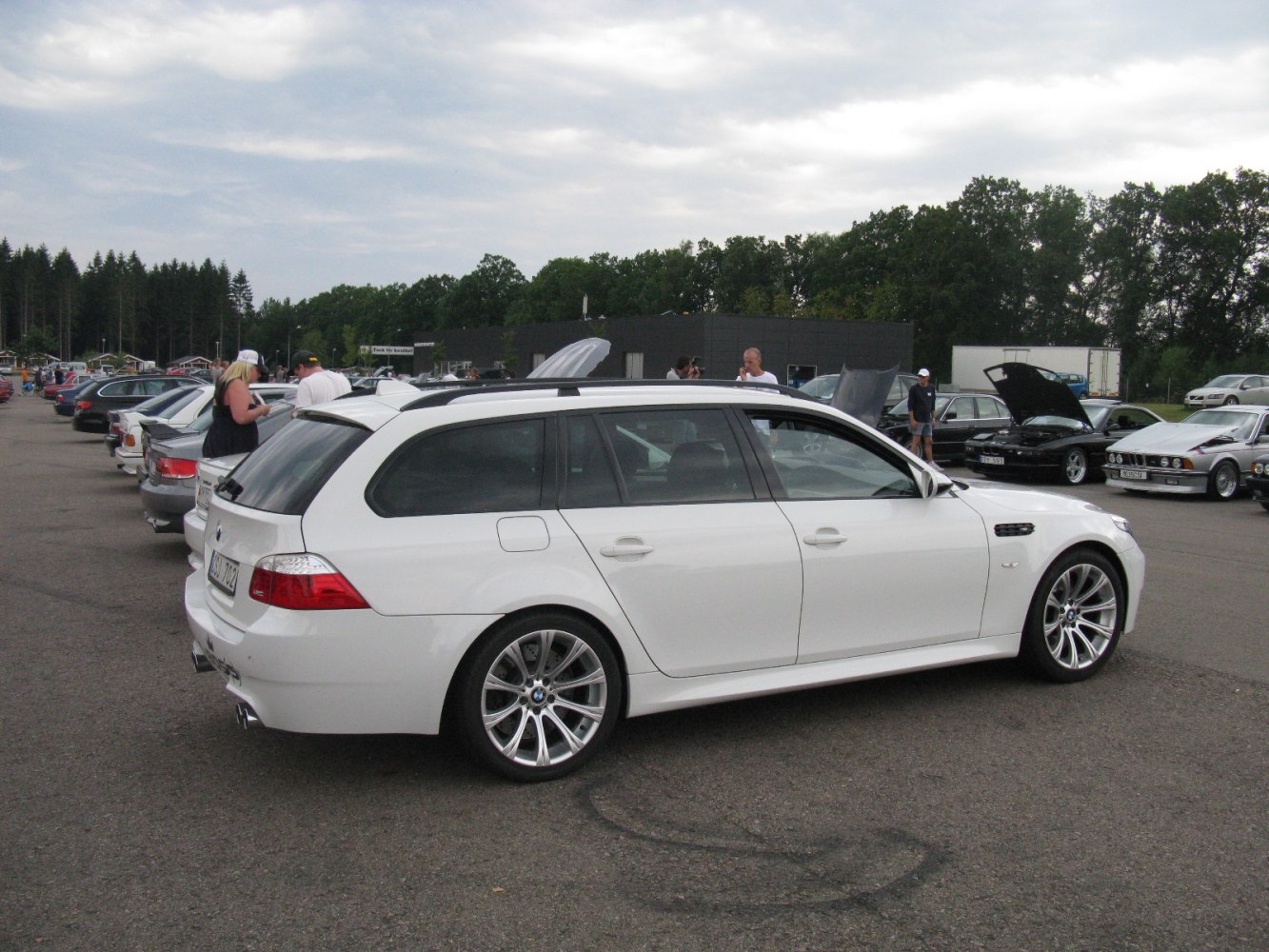 White sporty wagon with alloy wheels parked at a car meet.