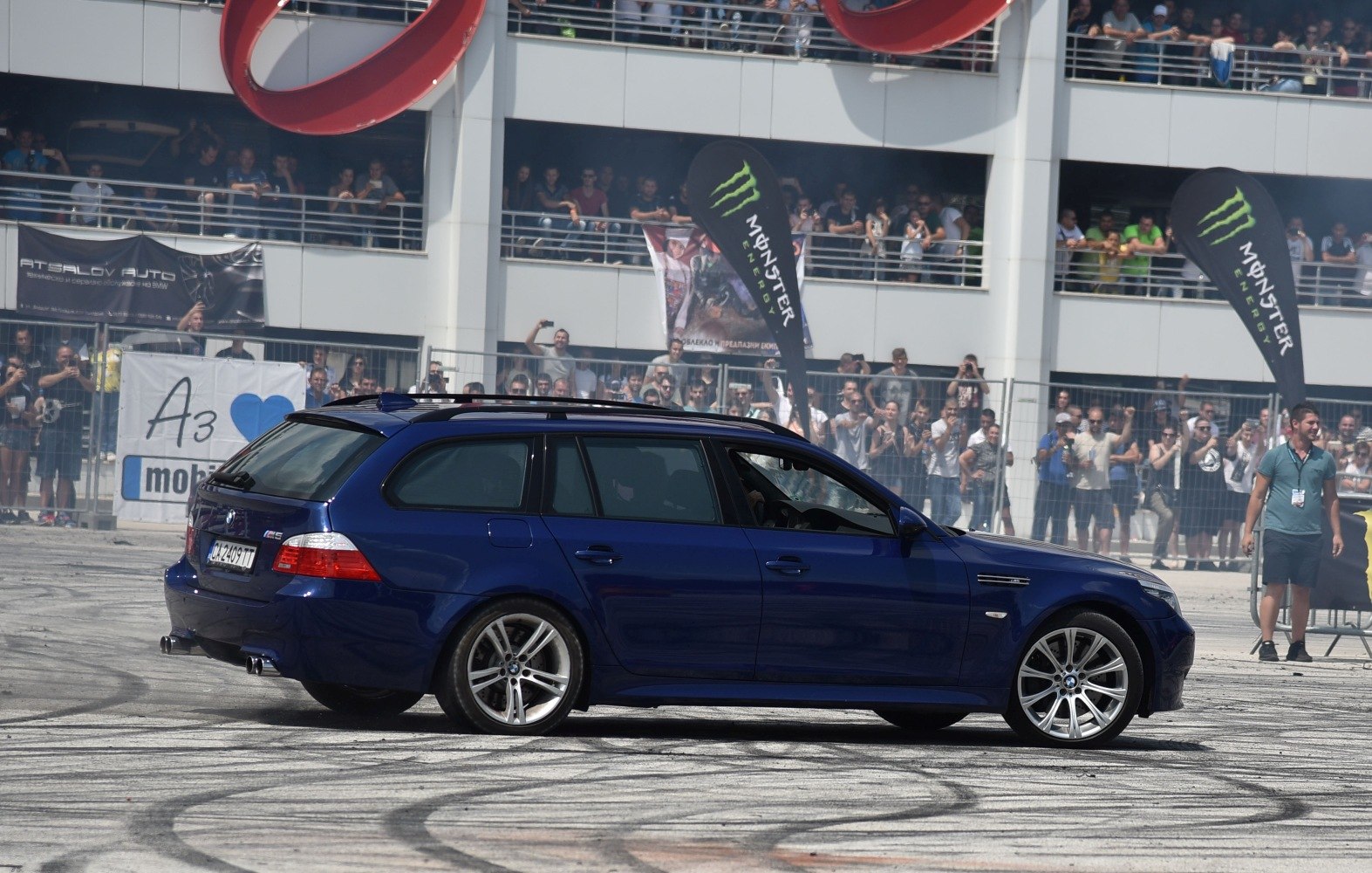 Side view of a blue estate car with sporty wheels and dual exhausts drifting on a track.