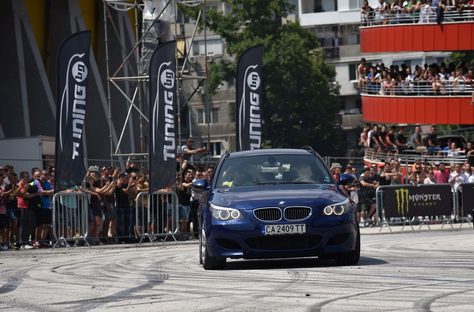 Front view of blue sports wagon with headlights on at motorsport event