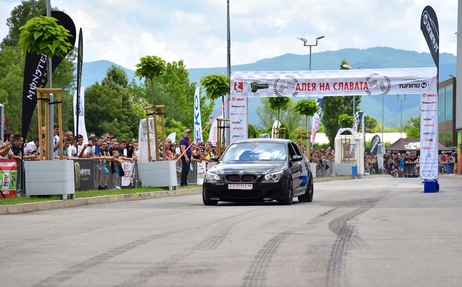 Black sports sedan with sporty wheels at a lively racing event