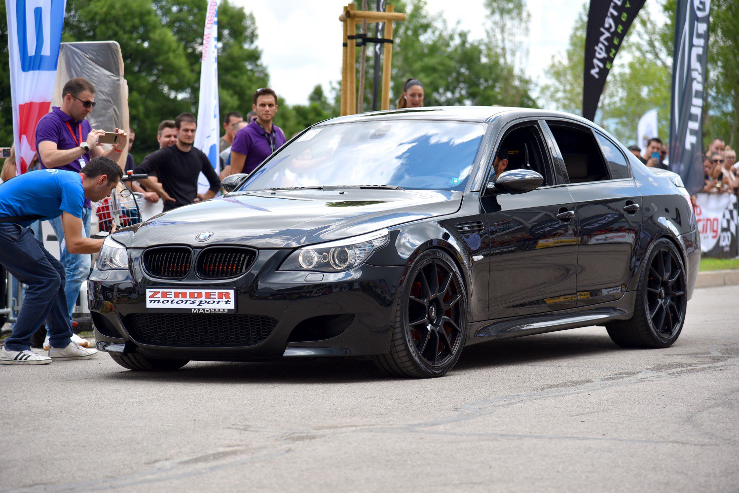 Black sporty sedan with custom black wheels and aggressive front grille