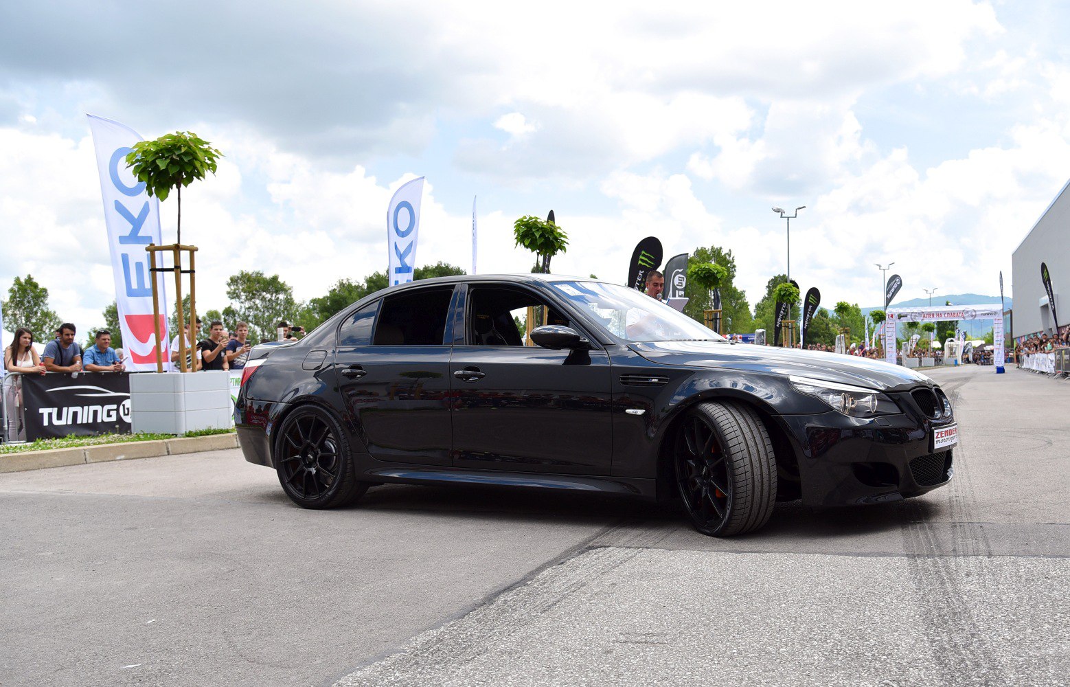 Black sedan with black alloy rims at car event