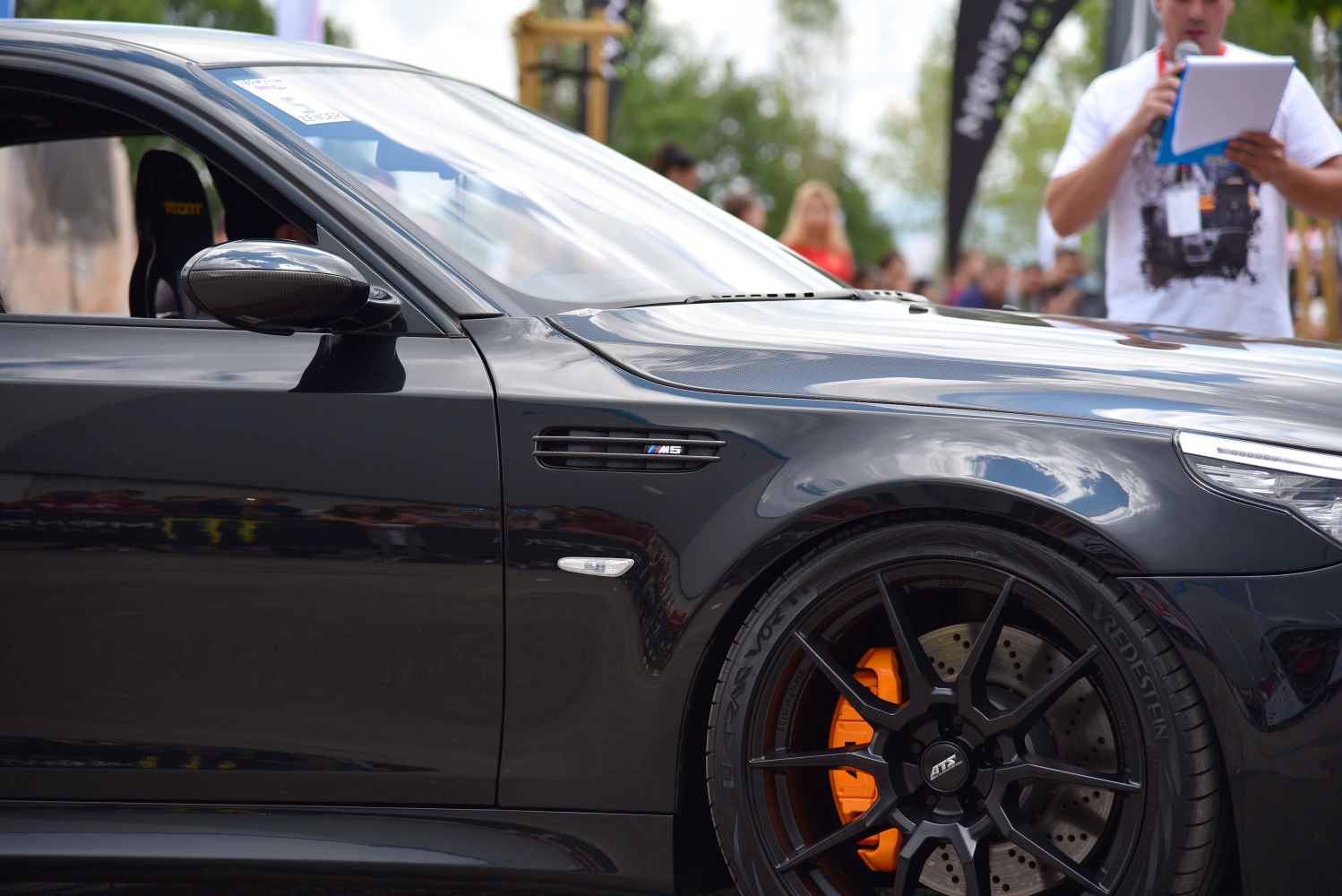 Black sport wheel with orange brake caliper and carbon fiber side mirror