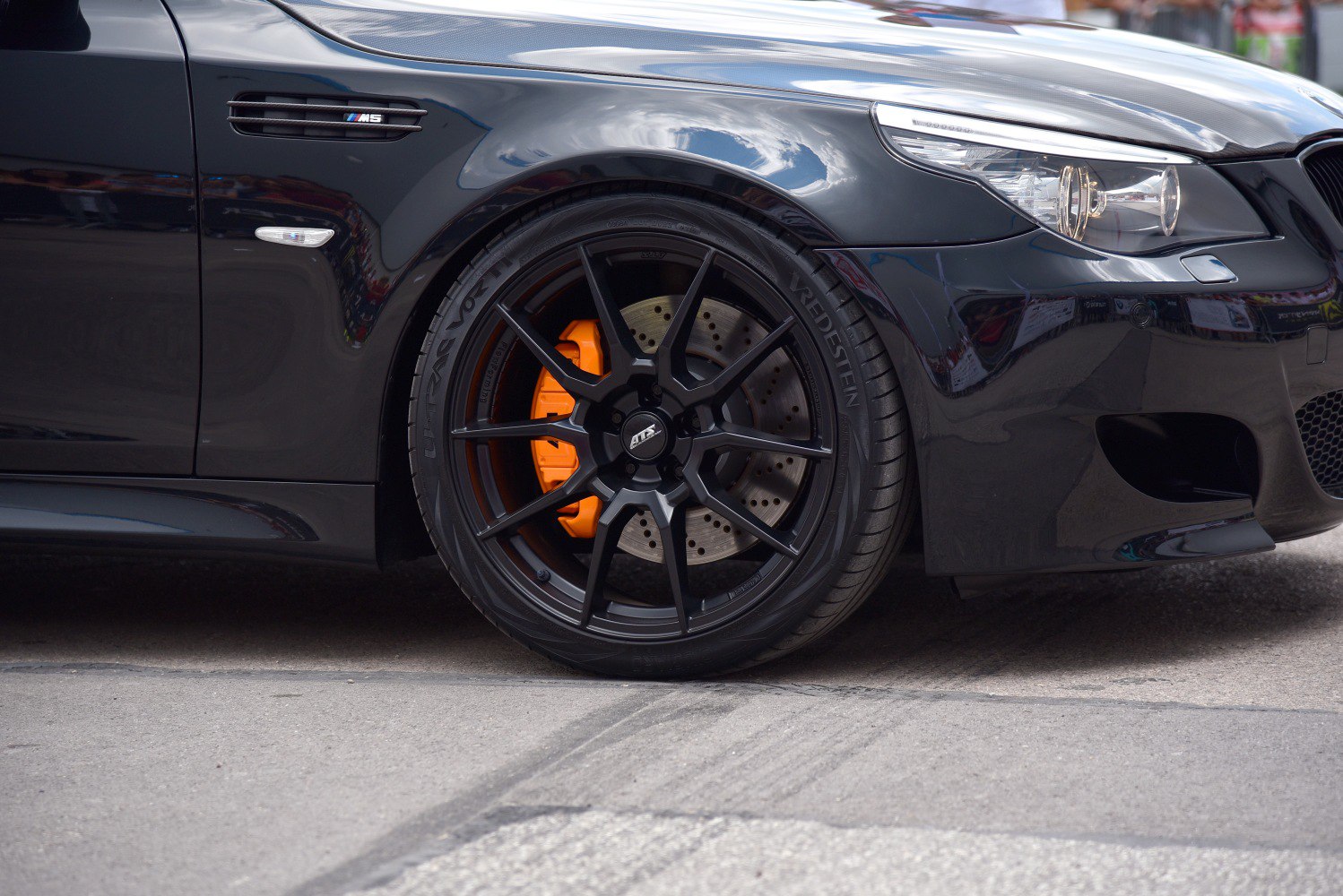 Close-up of black alloy rim with orange brake caliper and front headlight