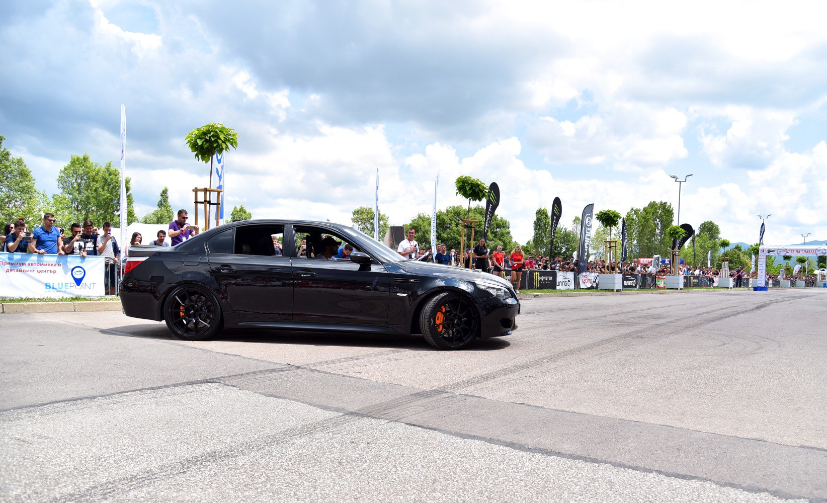 Black sedan with black wheels and orange calipers at car event