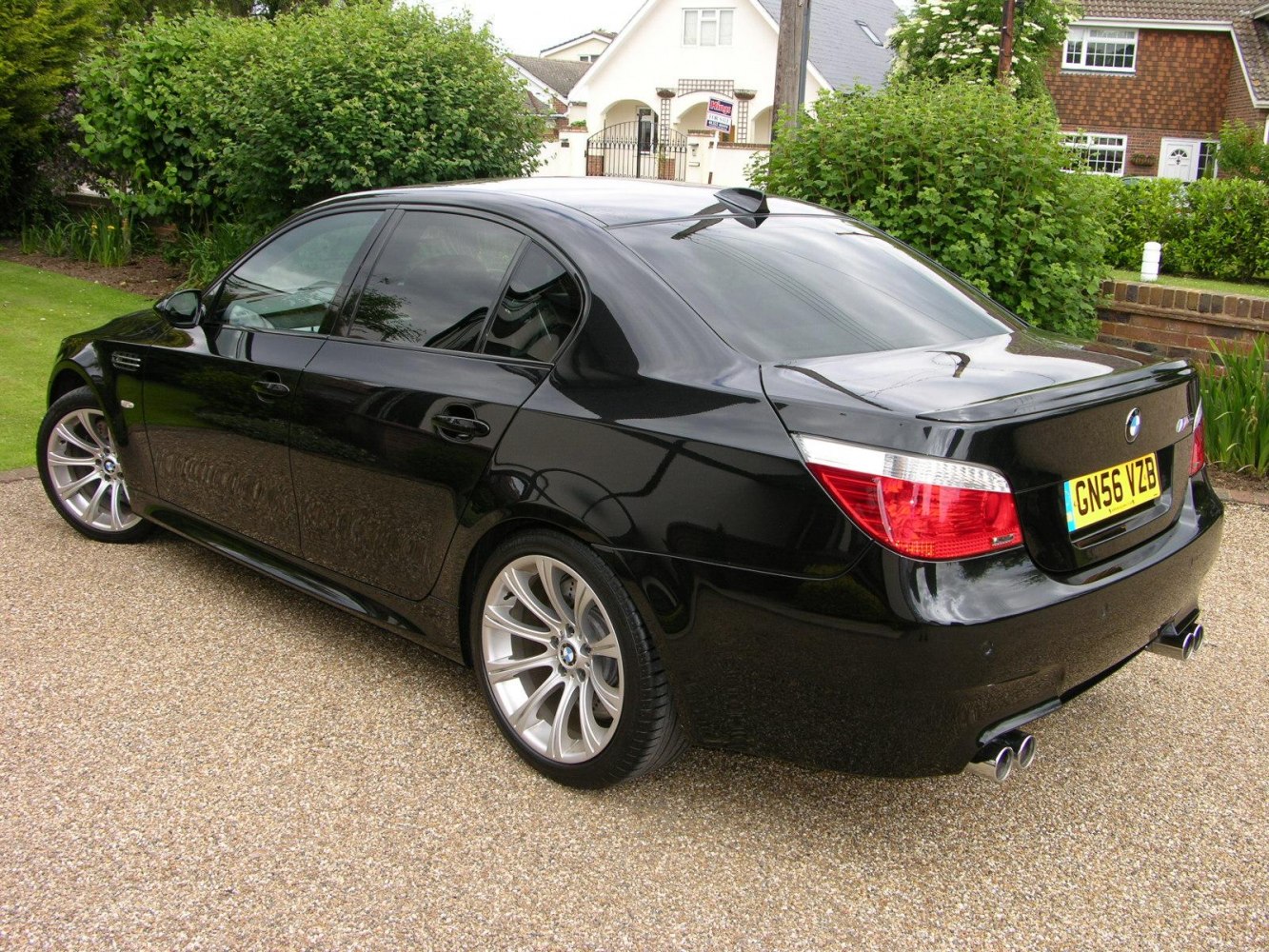 Rear-side view of black sedan with quad exhausts and rear spoiler lip