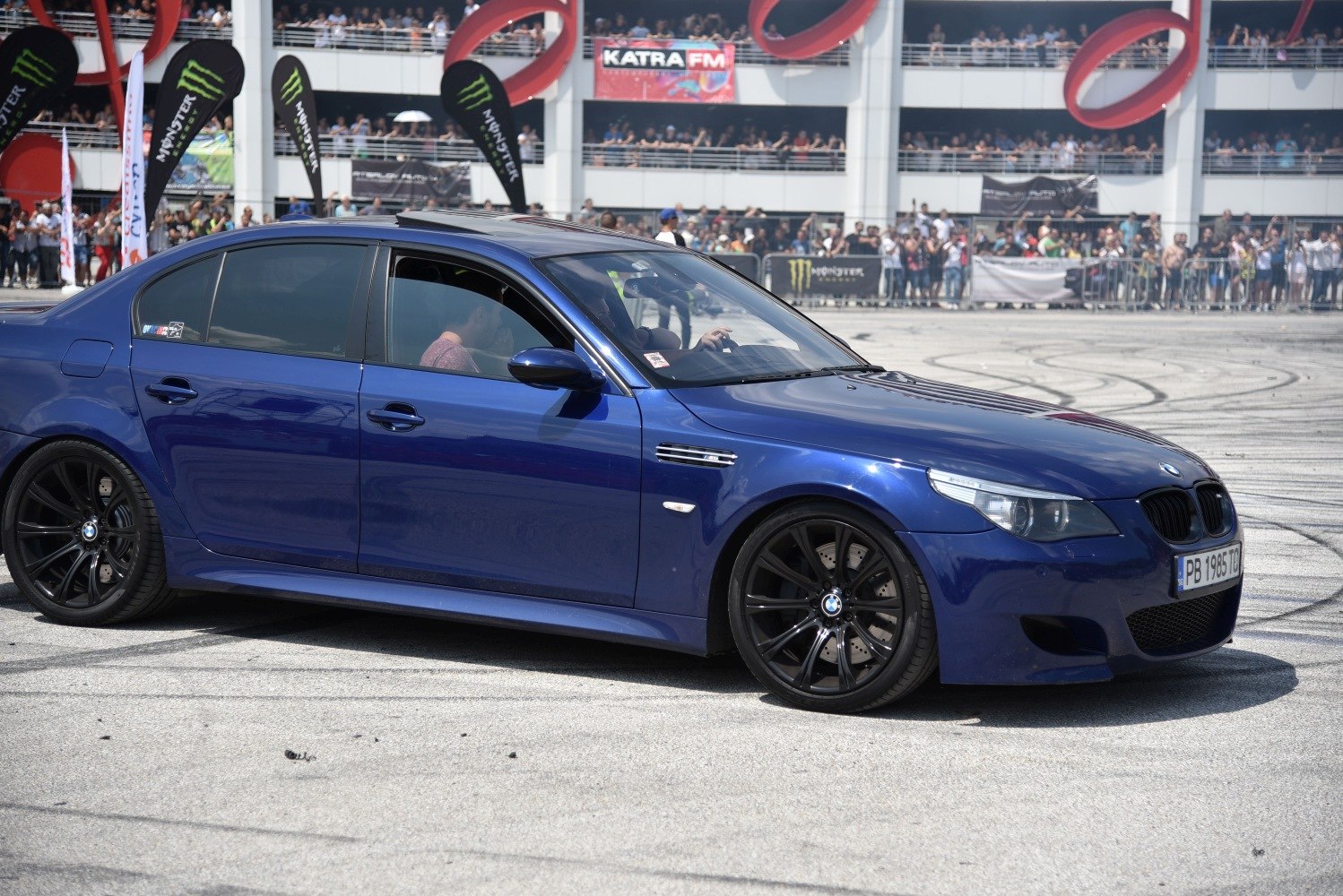 Blue sedan with black multi-spoke alloy wheels at automotive event.