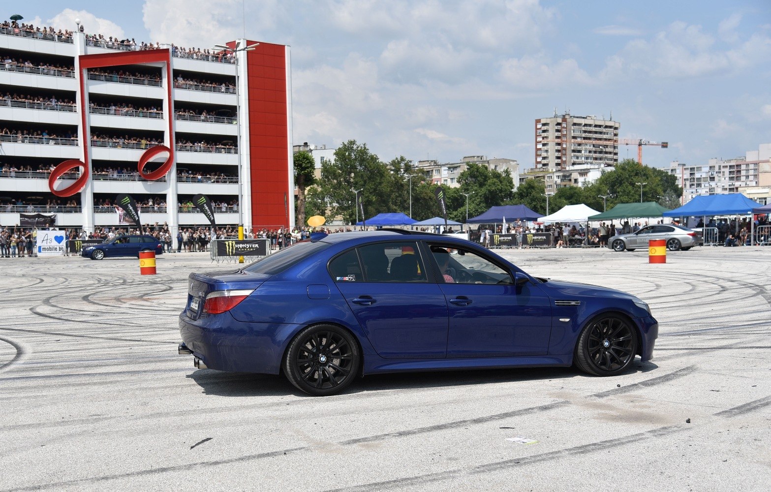 Side view of a blue sports sedan with black rims on event ground.