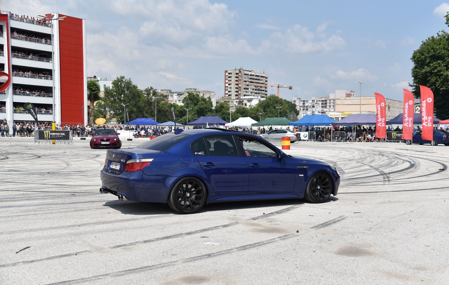 Blue performance sedan side view with black wheels on event track