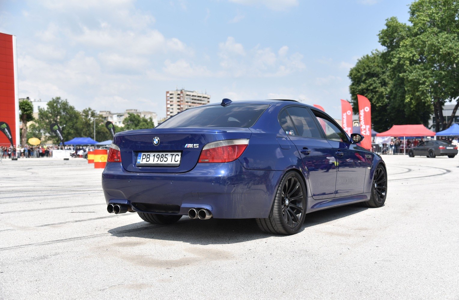 Rear view of a blue sedan with quad exhausts and black wheels.