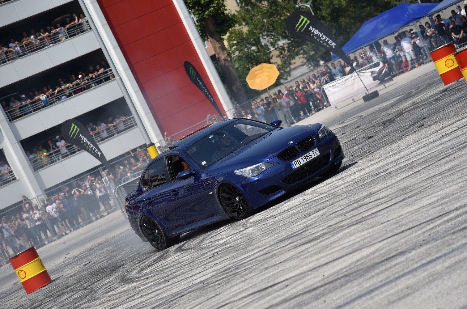 Blue sedan drifting on asphalt with black wheels at motorsport event