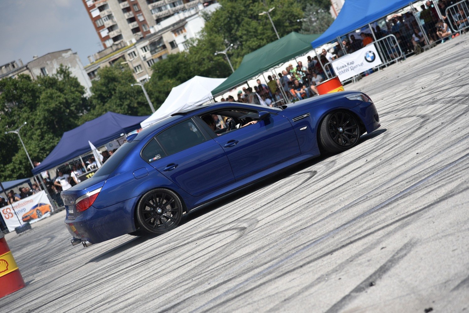 Blue sports sedan with black wheels performing drifting maneuvers