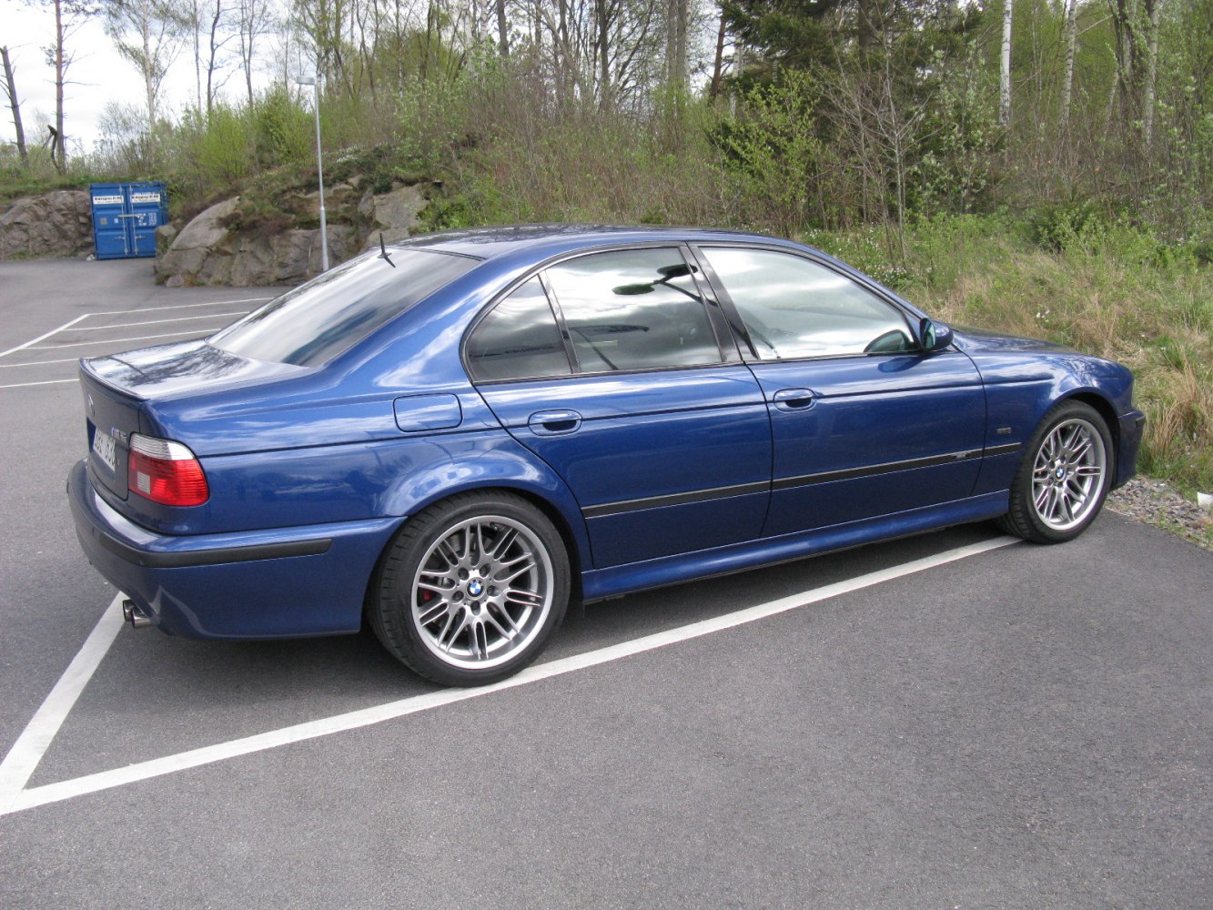 Blue BMW M5 sedan side view with sporty wheels and sleek body lines