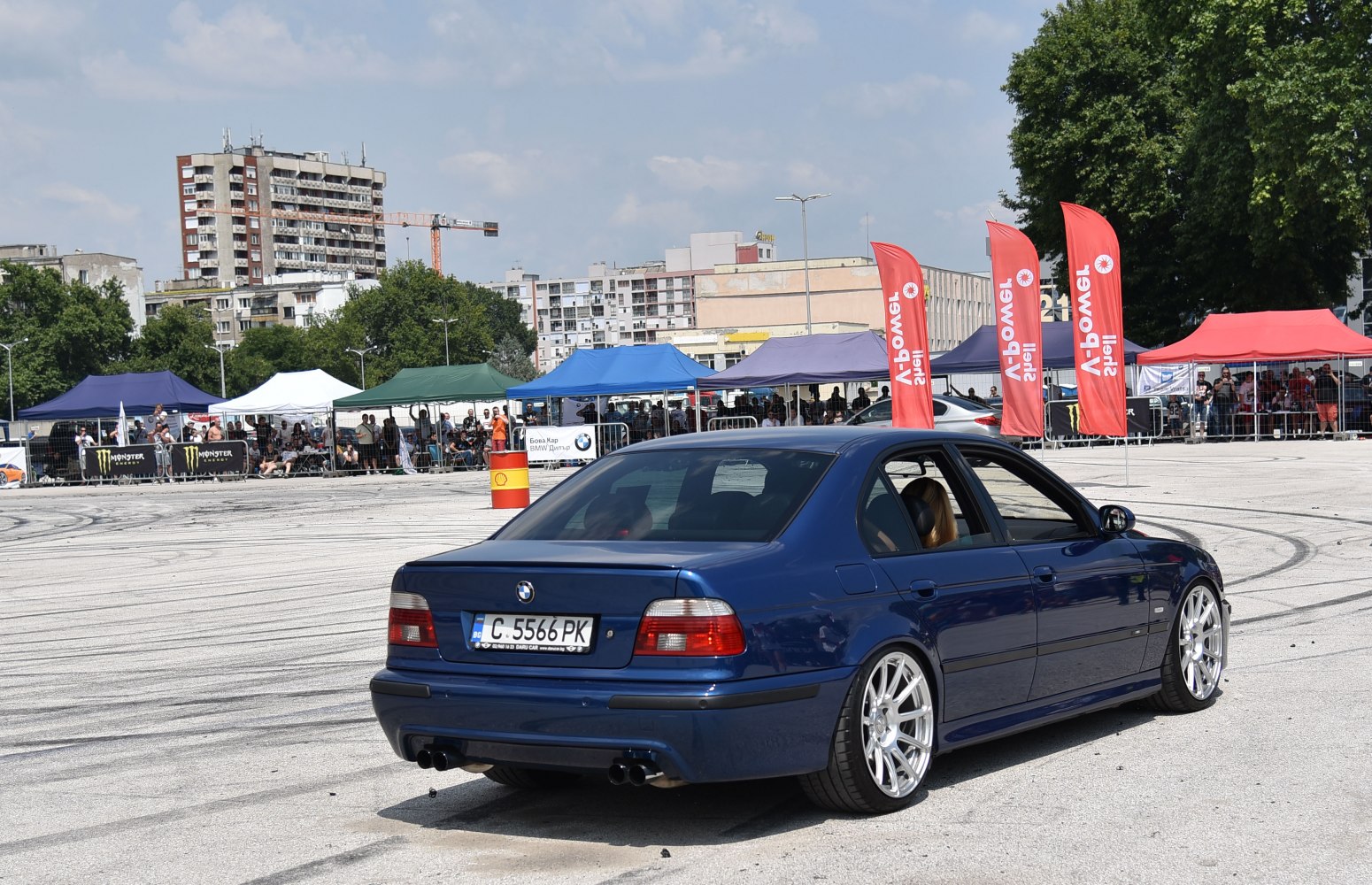 Rear and side view of blue sporty sedan with alloy wheels and dual exhaust