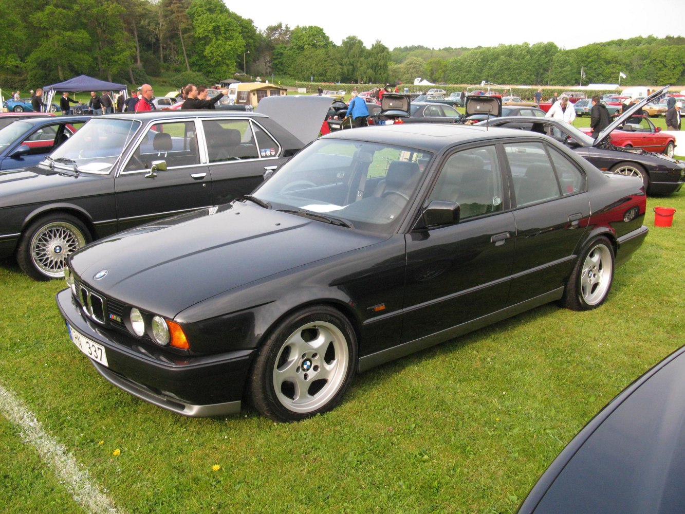 Front side view of a classic sedan with round headlights and five-spoke wheels