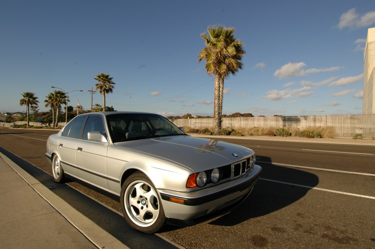 Silver sedan front-side view with alloy wheels on a sunny street
