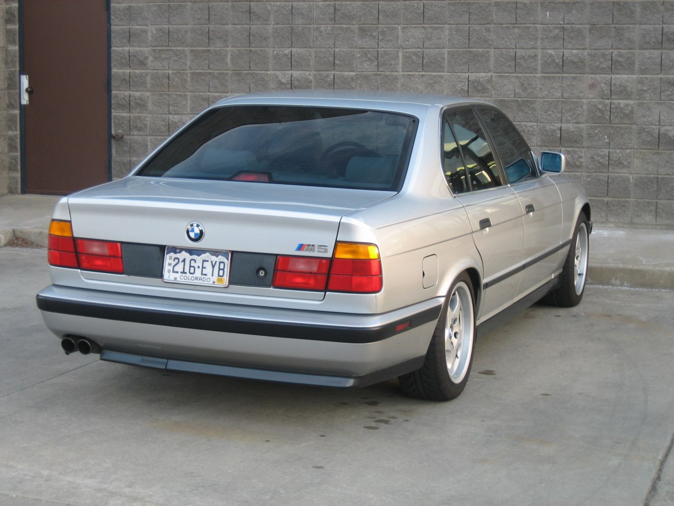 Silver sedan rear with badge, tail lights, and dual exhaust