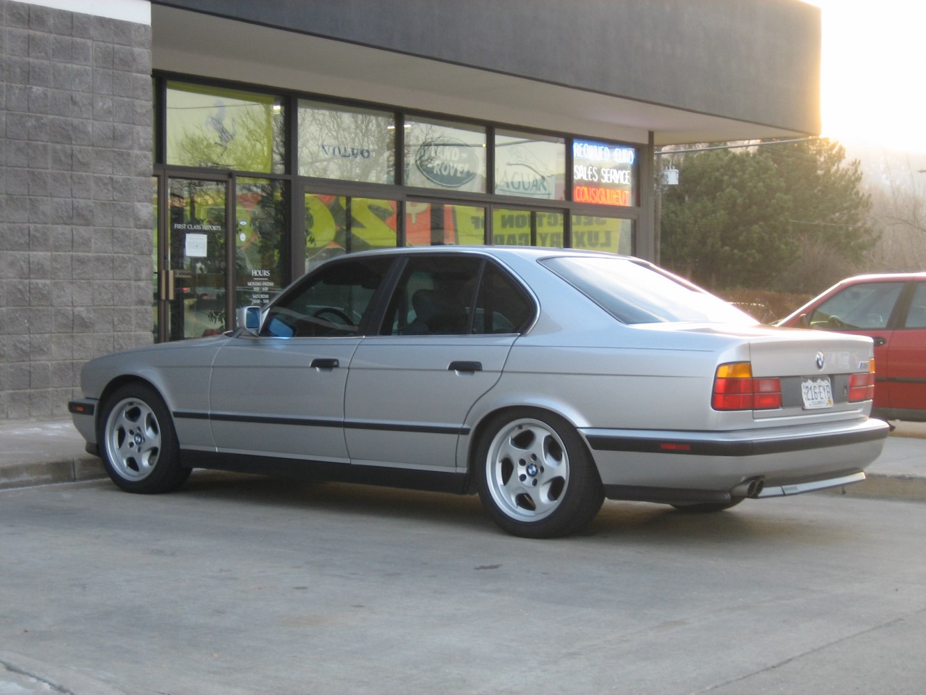 Silver luxury sedan with five-spoke wheels, rear-side view from late 80s to early 90s