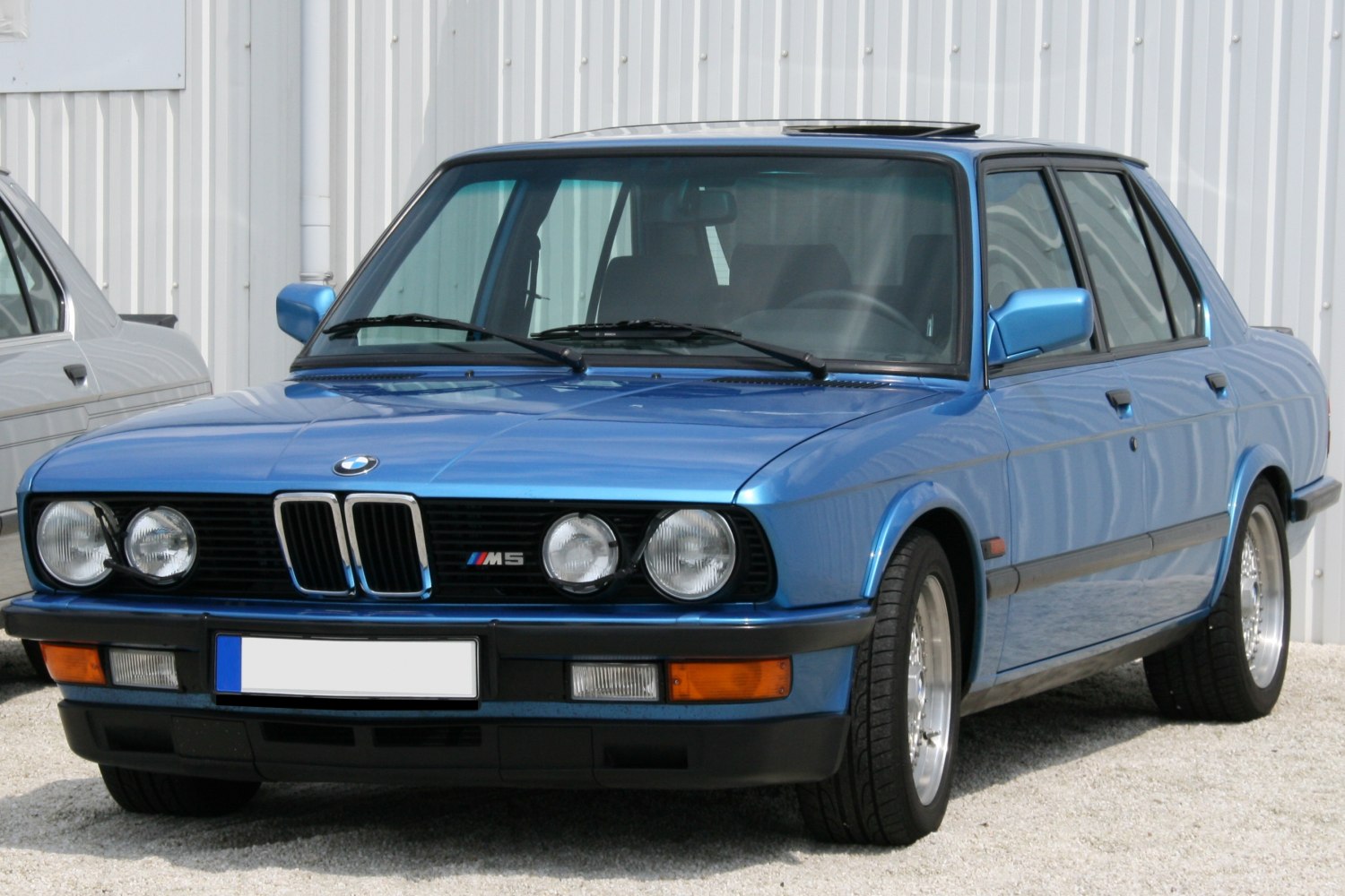 Front view of blue BMW M5 E28 with quad headlights and kidney grille