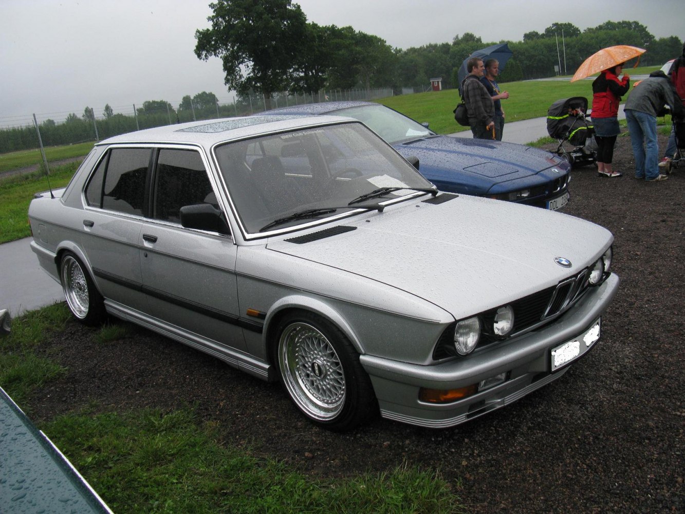 Silver 1980s sedan with quad headlights and multi-spoke wheels
