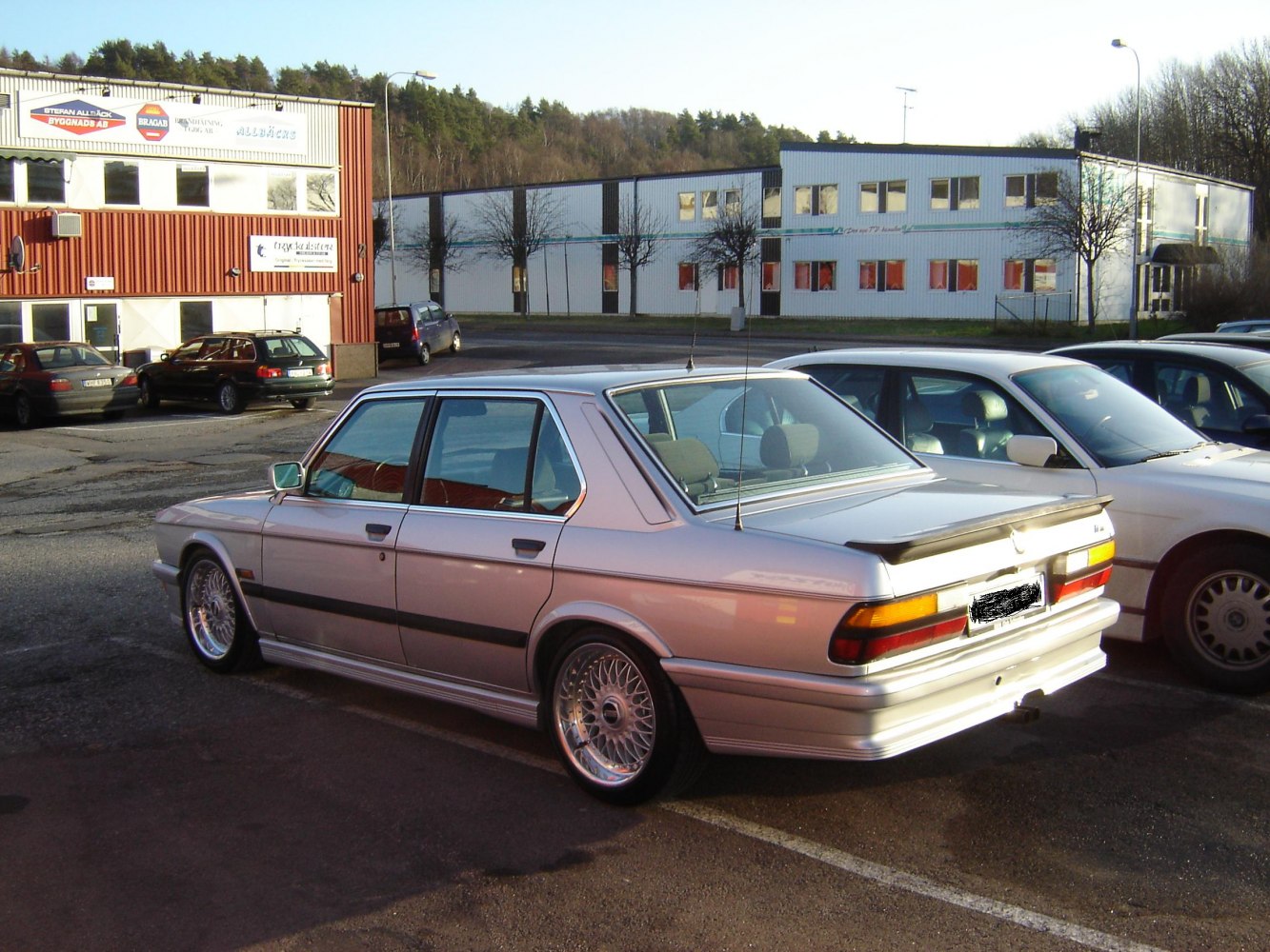 Silver classic sedan rear side view with alloy wheels and rear spoiler