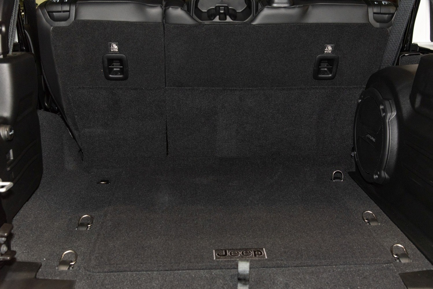 Spacious black carpeted cargo area with Alpine subwoofer