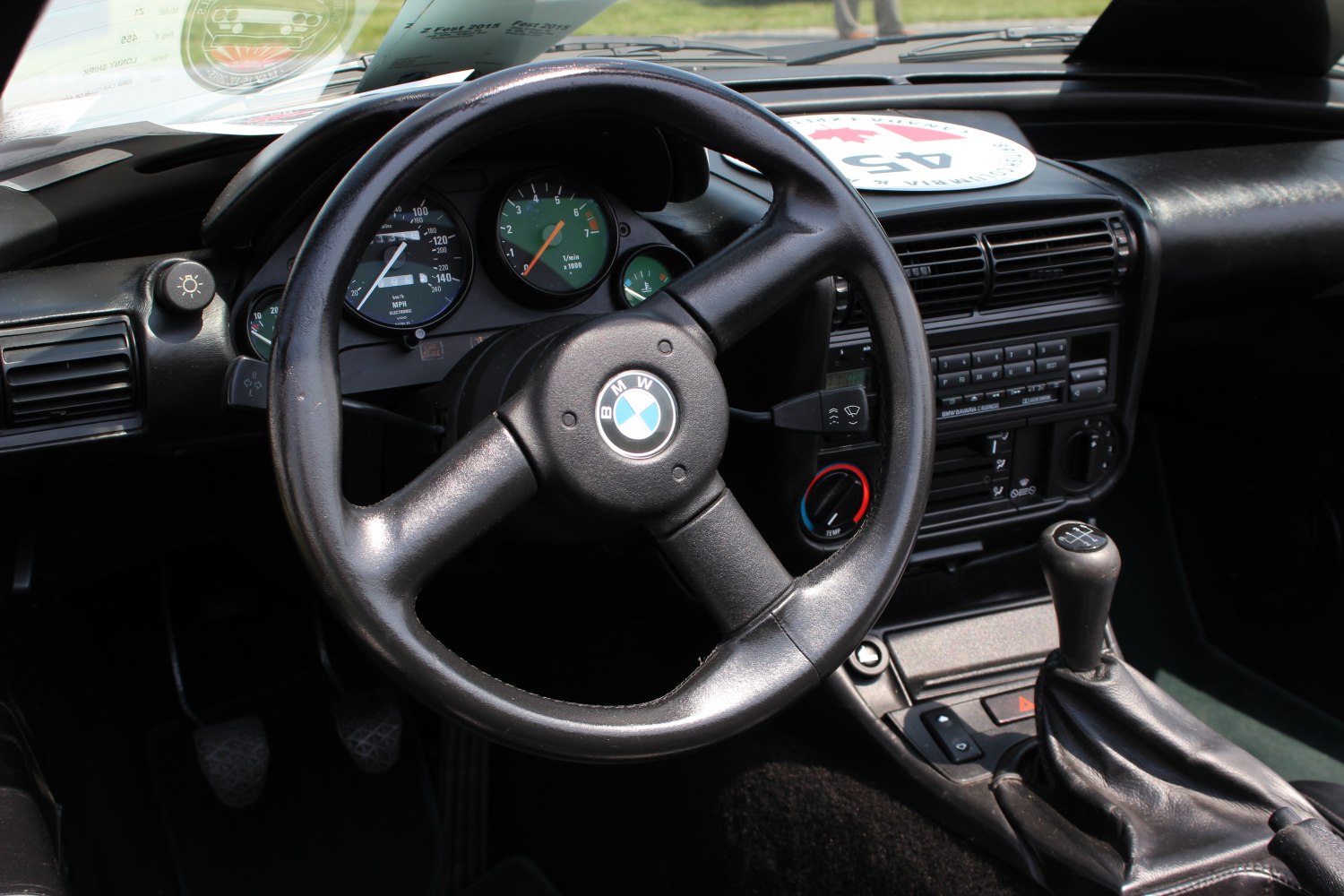 Steering wheel, dashboard, manual gear shift, and gauge cluster of a classic car interior
