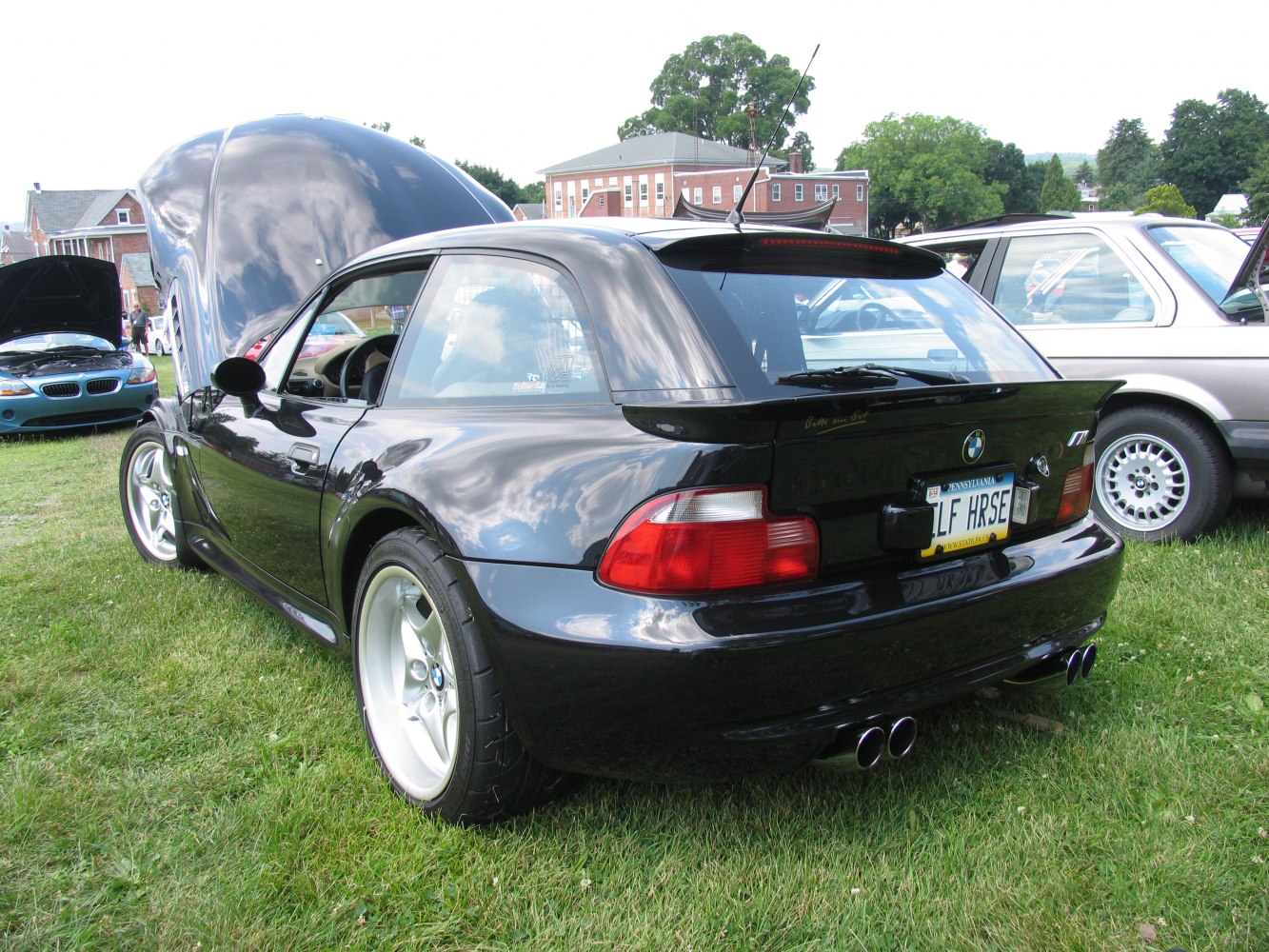 Rear and side view of black coupe with quad exhaust and wide wheels.