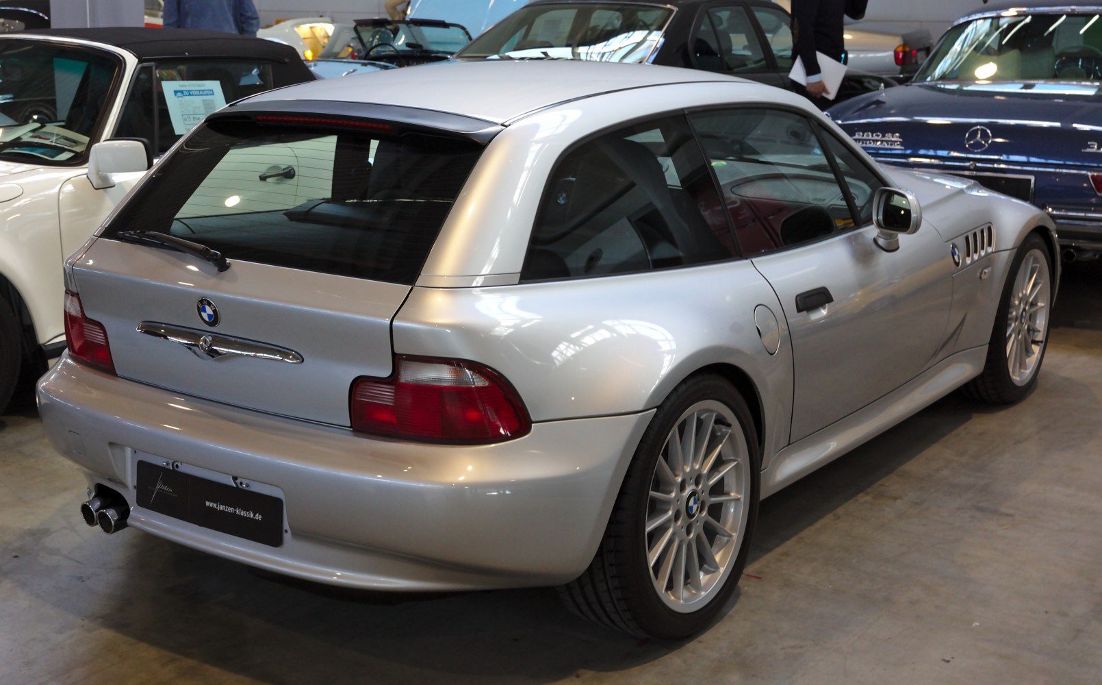Rear view of silver coupe, tail lights and alloy wheels.