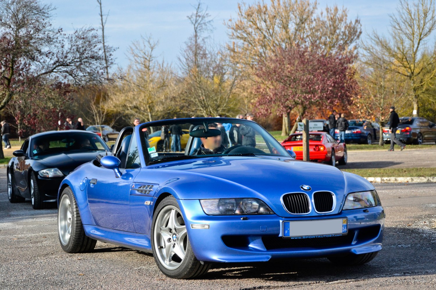 Blue sporty roadster with open roof and prominent front grille
