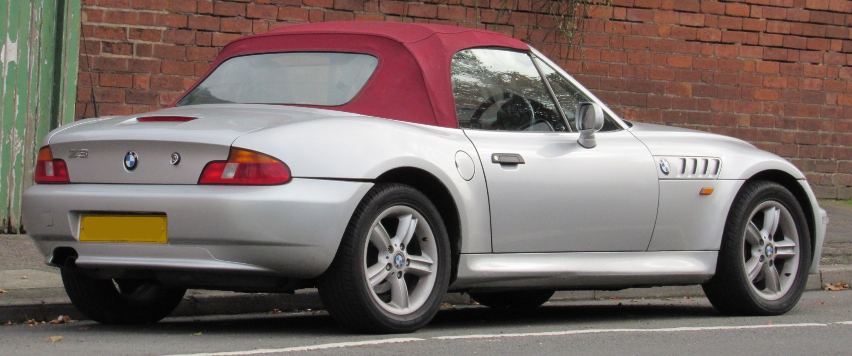 Silver roadster with red soft top, alloy wheels, and distinctive rear design.