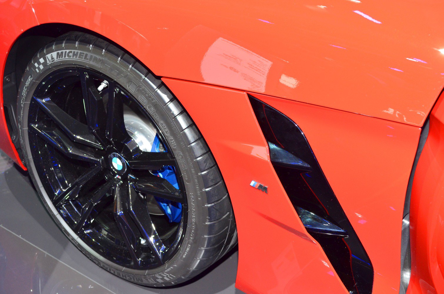 Close-up of black alloy wheel with Michelin tire and sporty side vent with M badge