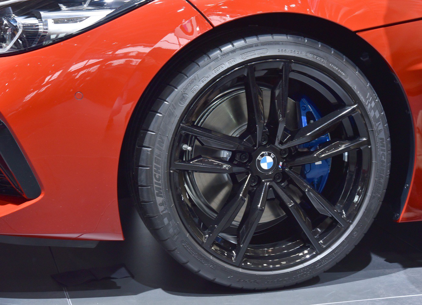 Black alloy wheel with blue brake caliper and tire sidewall.