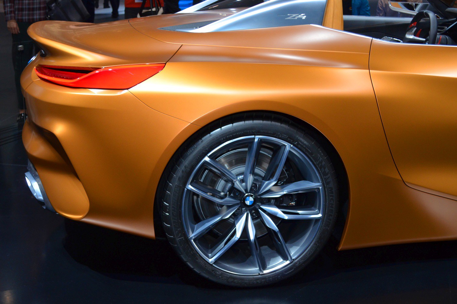 Rear wheel and taillight of a sports car in metallic orange.