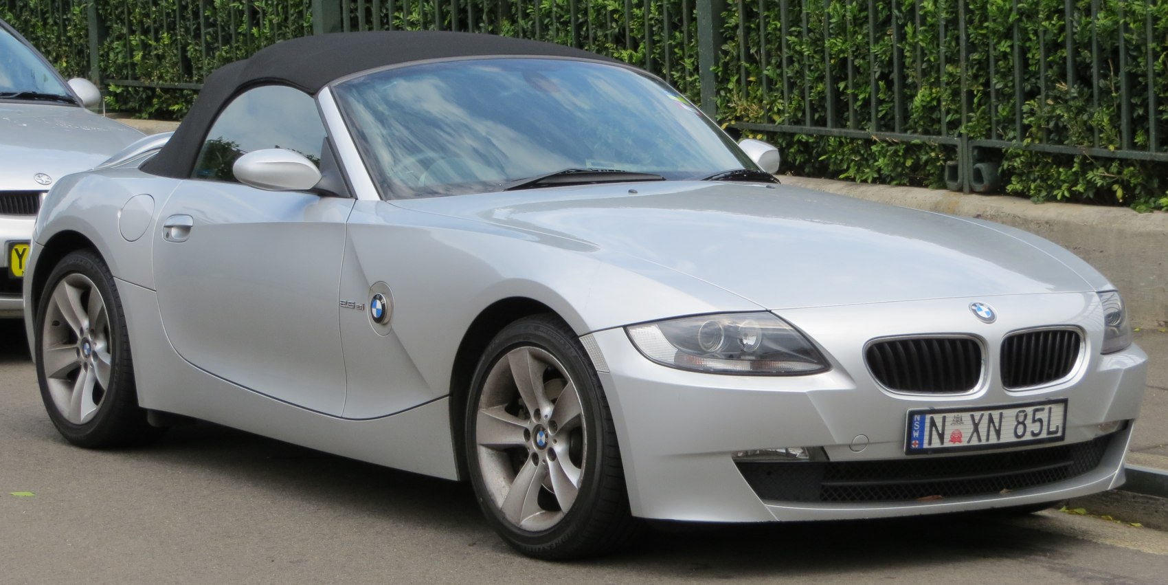 Silver convertible with black soft top, sleek front side profile and sporty alloy wheels.