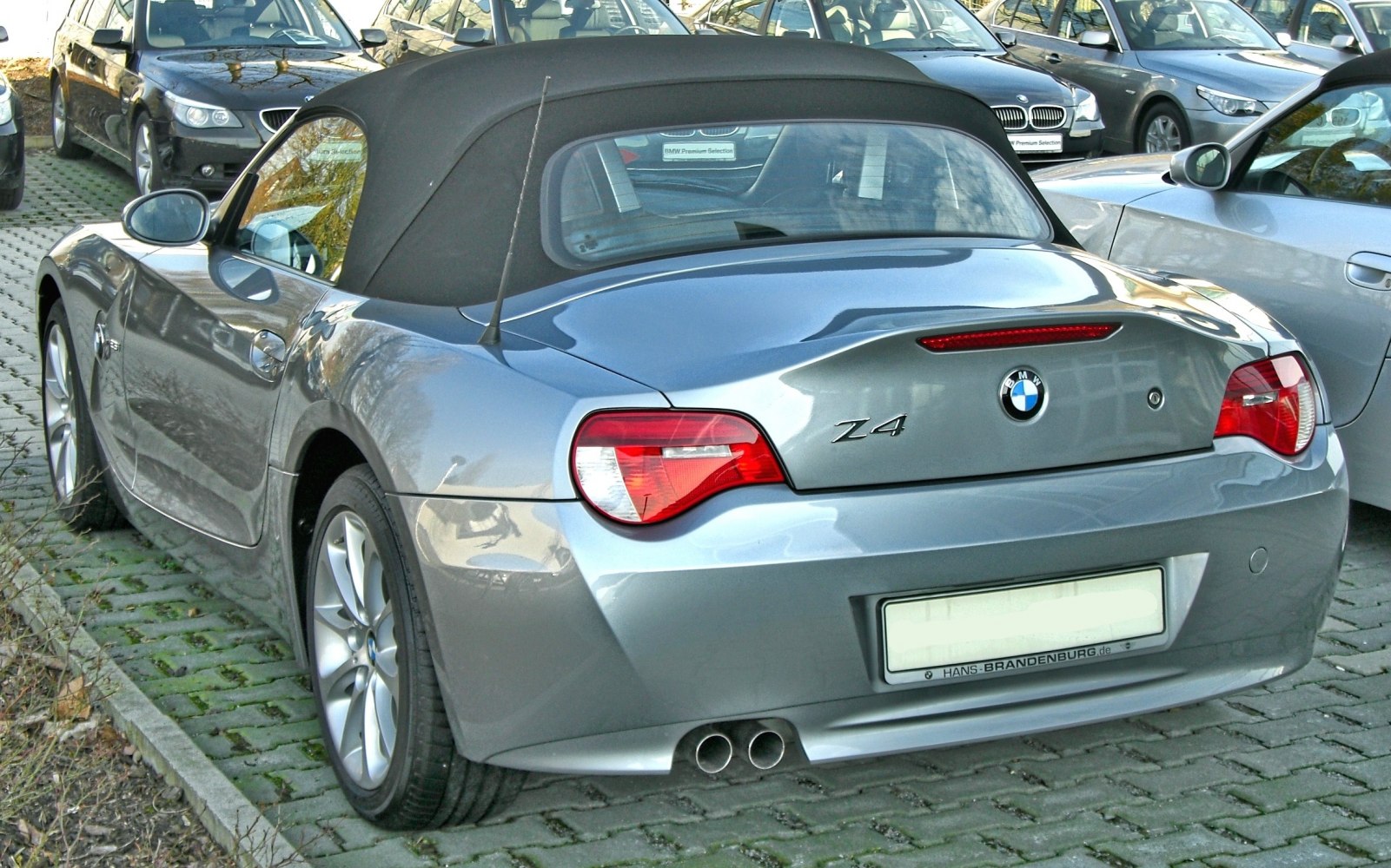 Rear view of silver convertible with dual exhaust and modern taillights