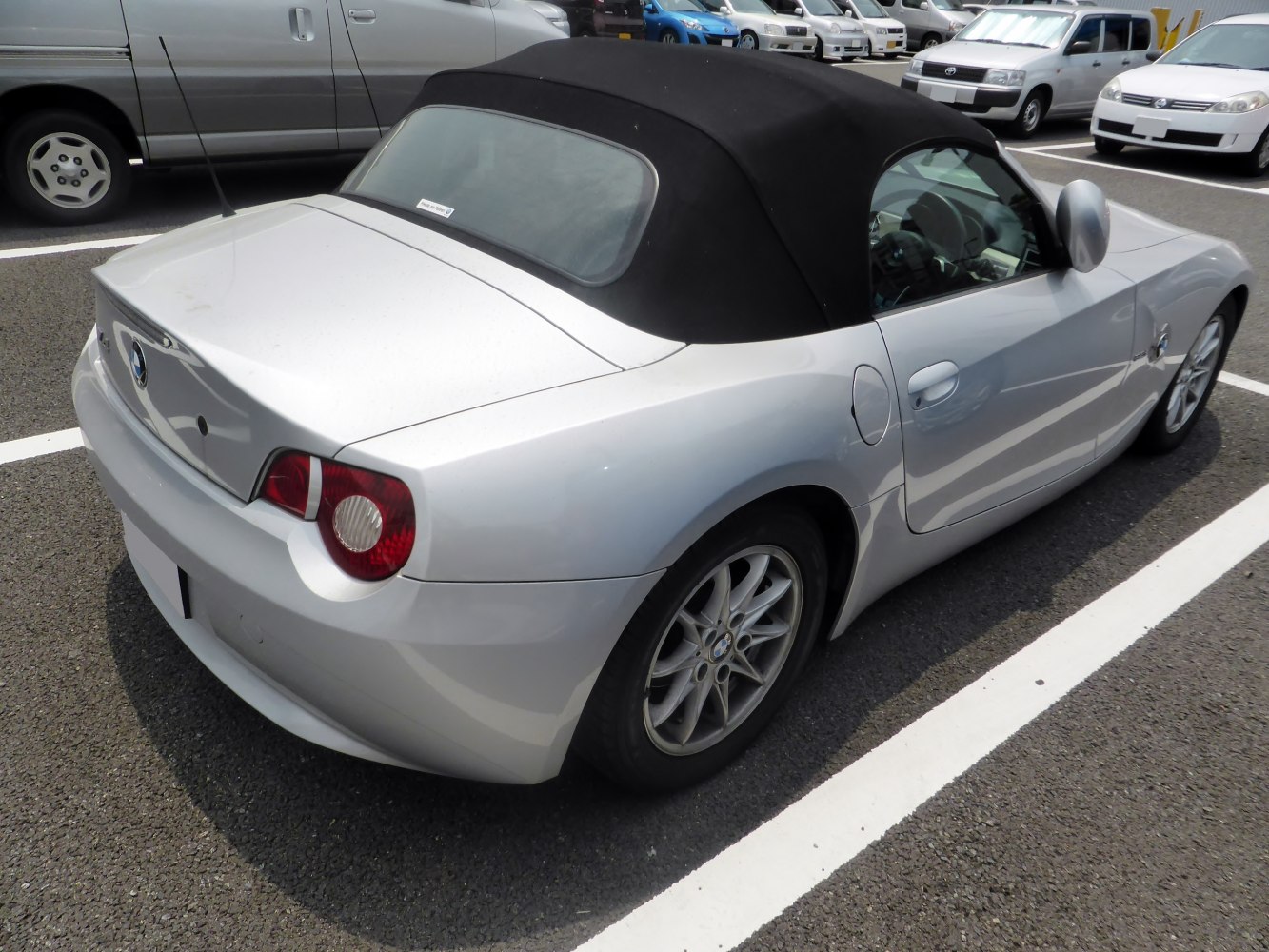Rear-side view of a silver convertible with black soft top