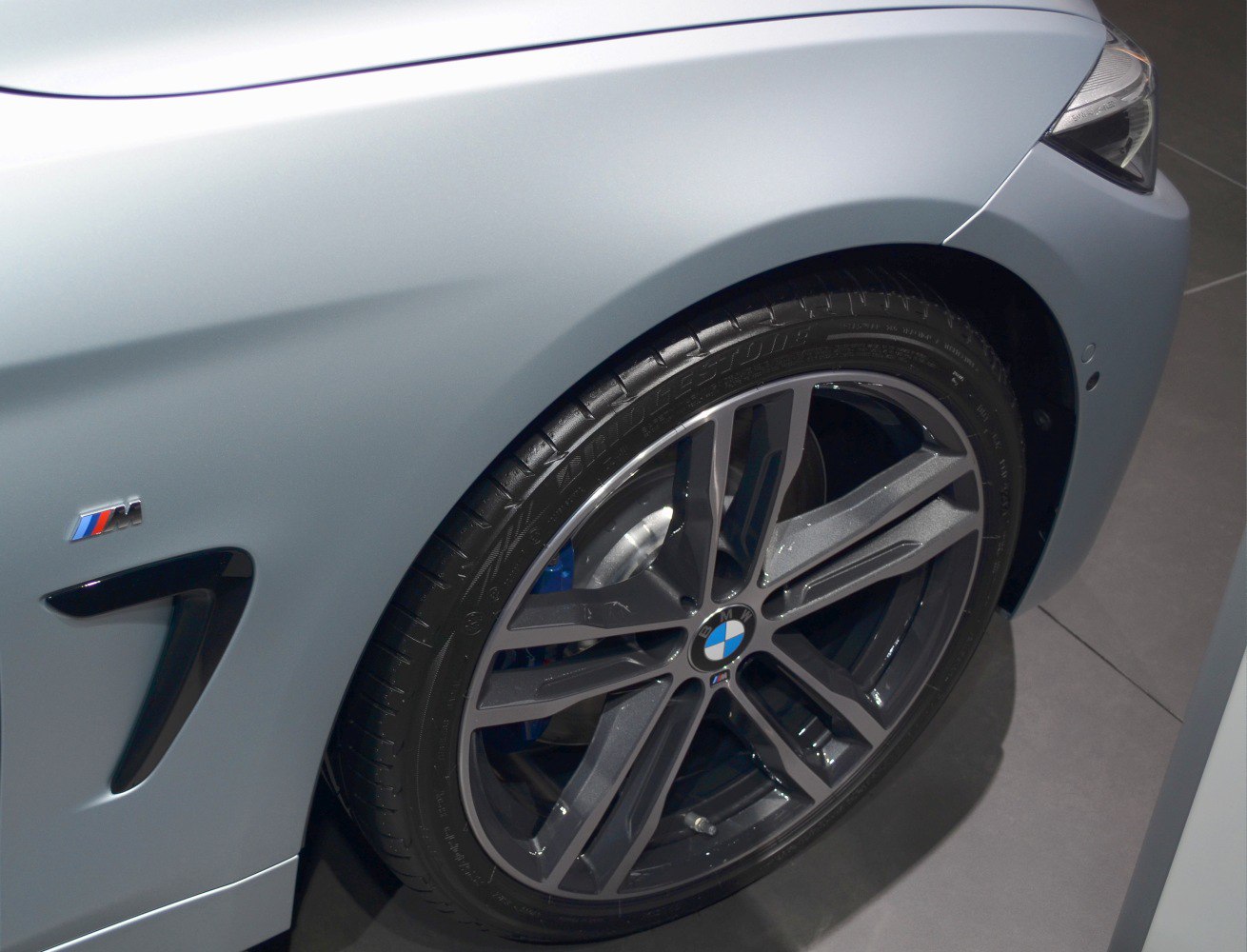Close-up of alloy wheel and M badge on front side panel.