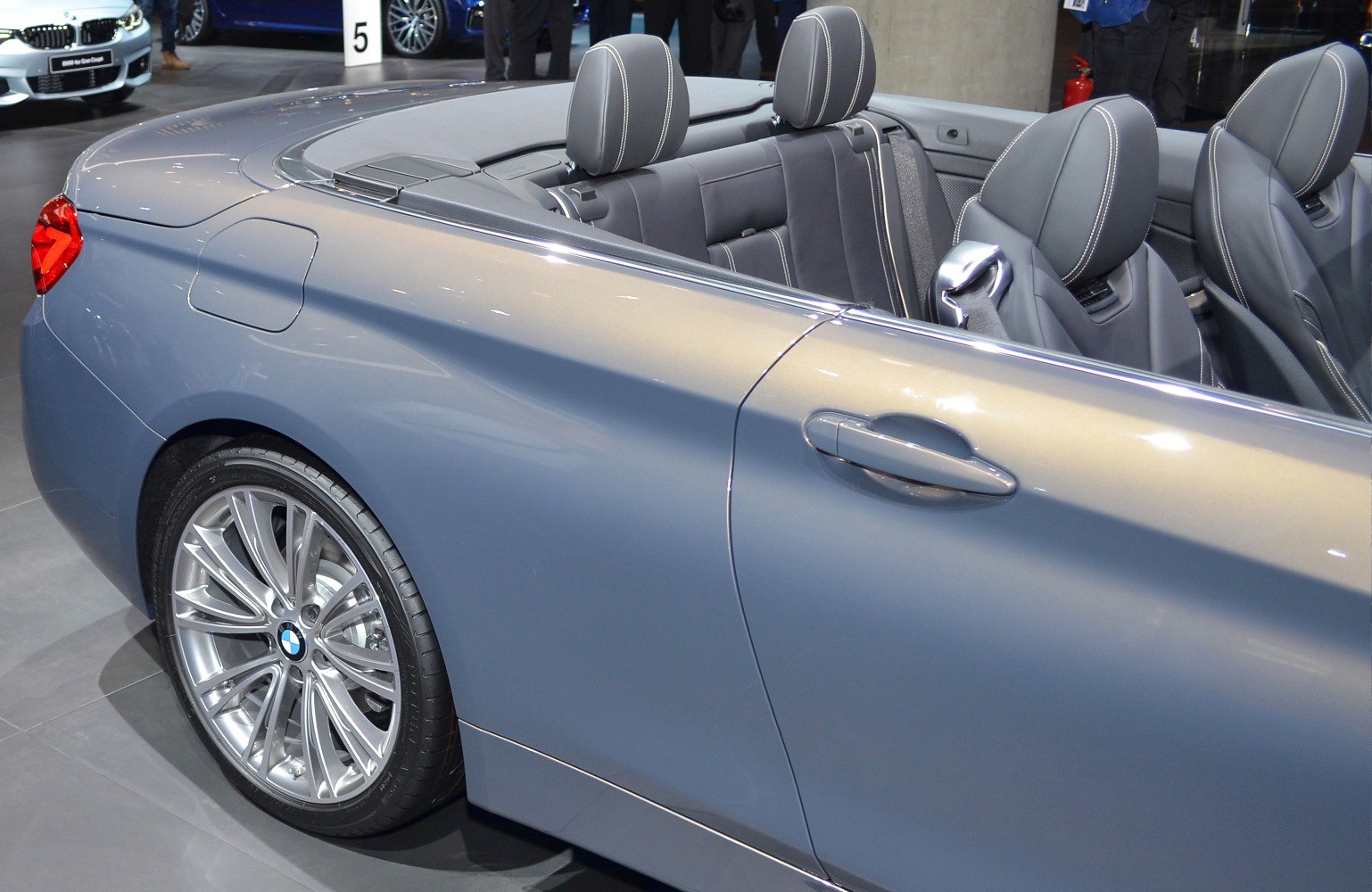 Rear side and interior view of an open roof convertible with alloy wheels and headrests.