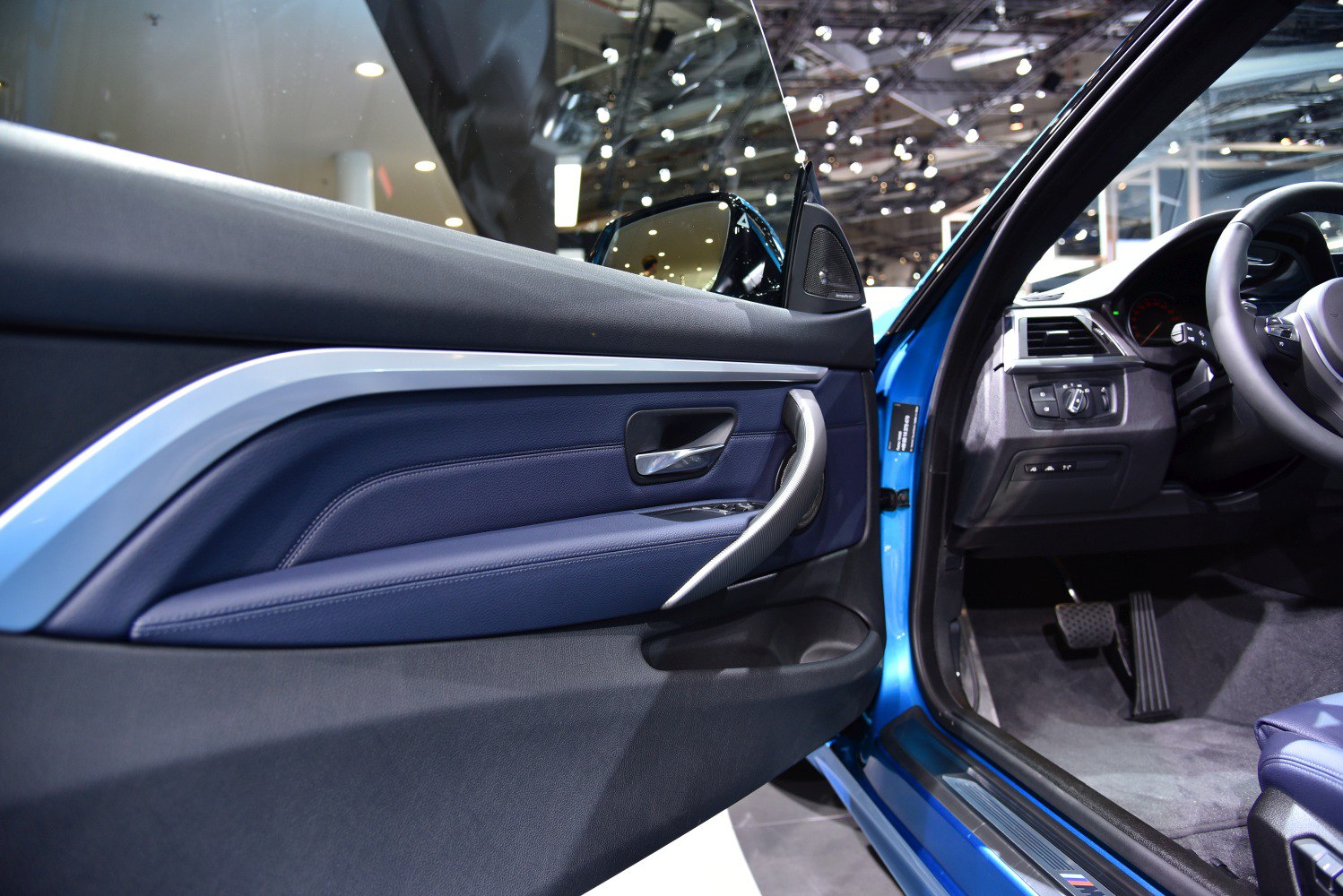 Interior door panel with blue leather, door handle, and driver controls